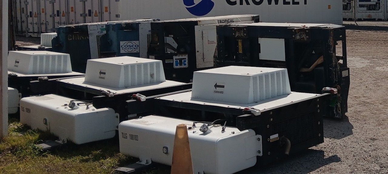 A collection of large, black industrial units topped with white, rectangular boxes; outside.