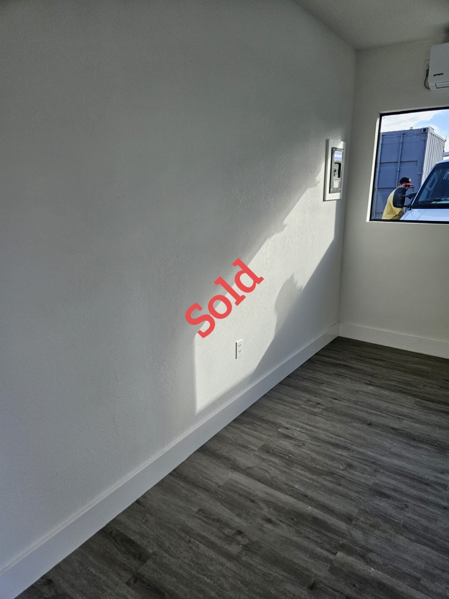 Empty room with white walls, wood-look floor, window, and 