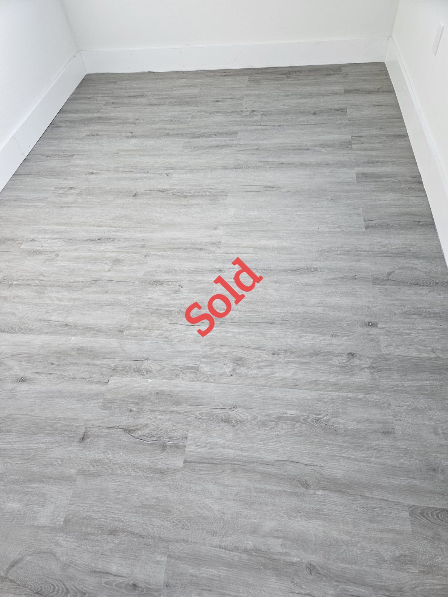 Gray wood-look flooring with white baseboards and walls. 
