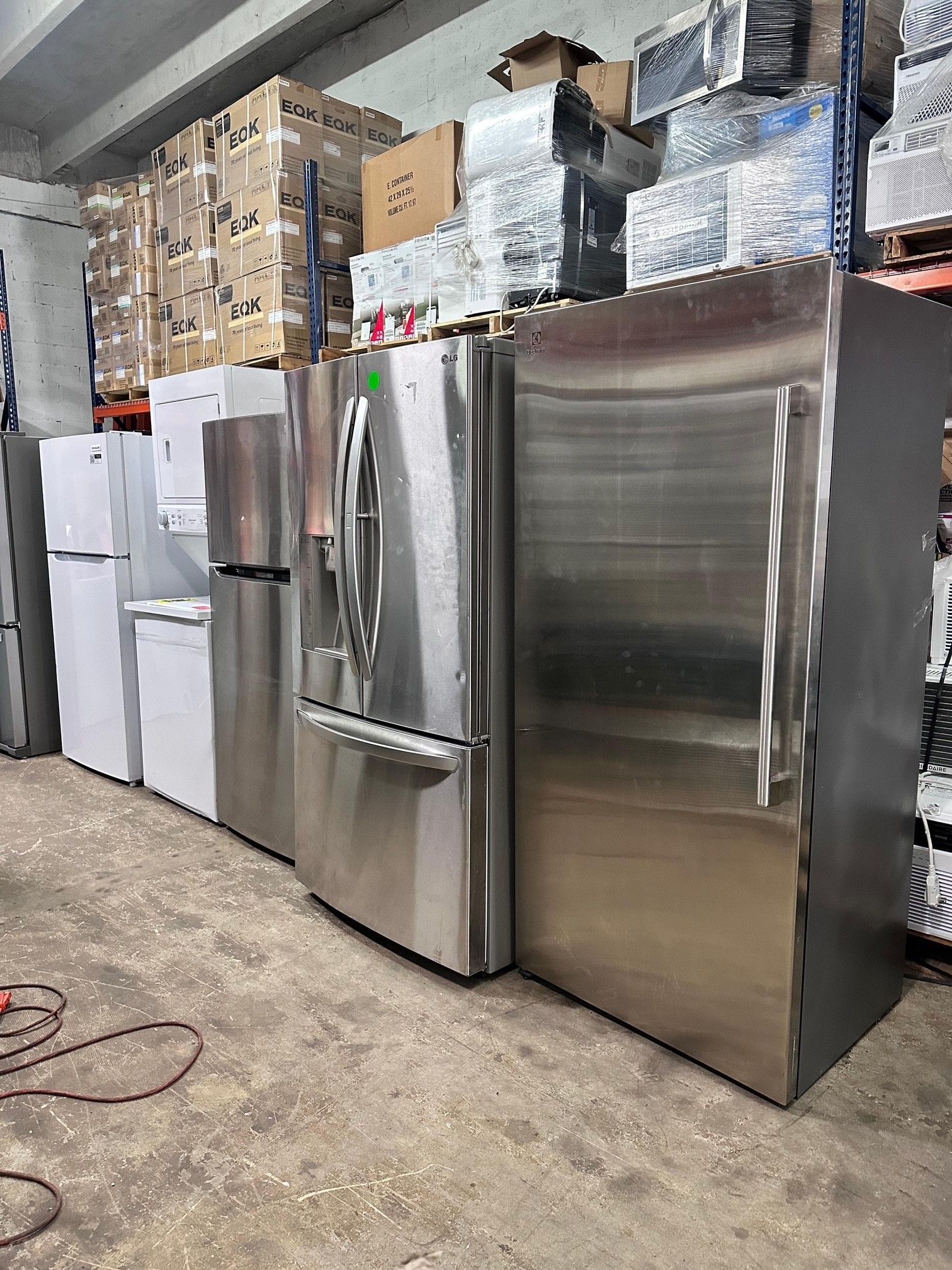 Refrigerators of various sizes and styles in a warehouse setting.
