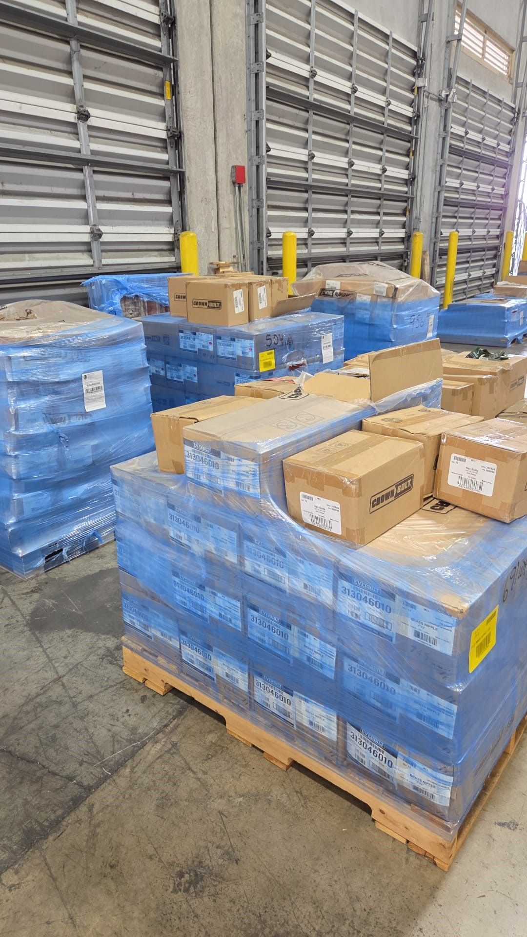 Pallets wrapped in blue plastic containing boxes in a warehouse.