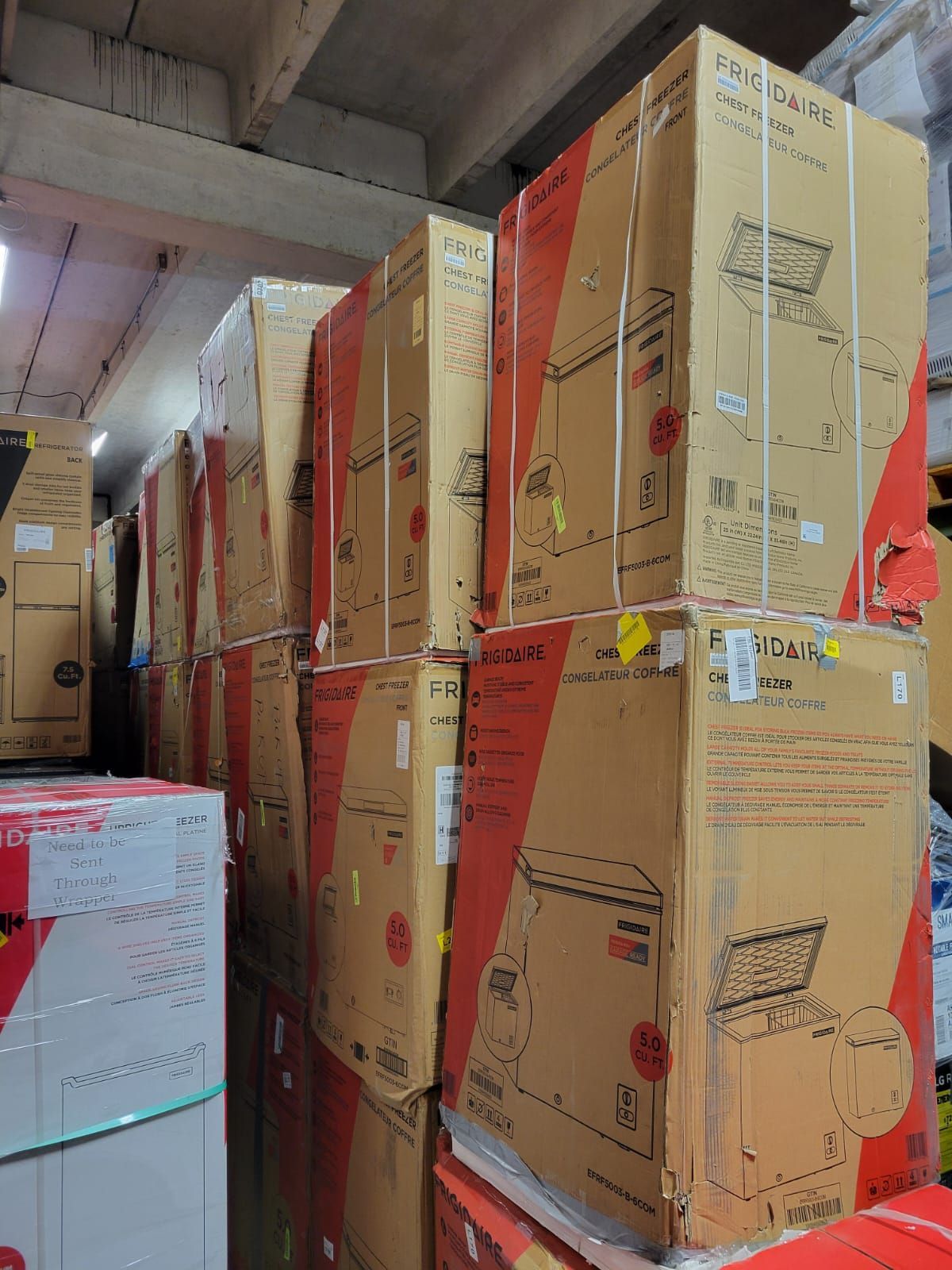 Cardboard boxes stacked in a warehouse. Boxes are brown with red accents, likely for appliances or electronics.