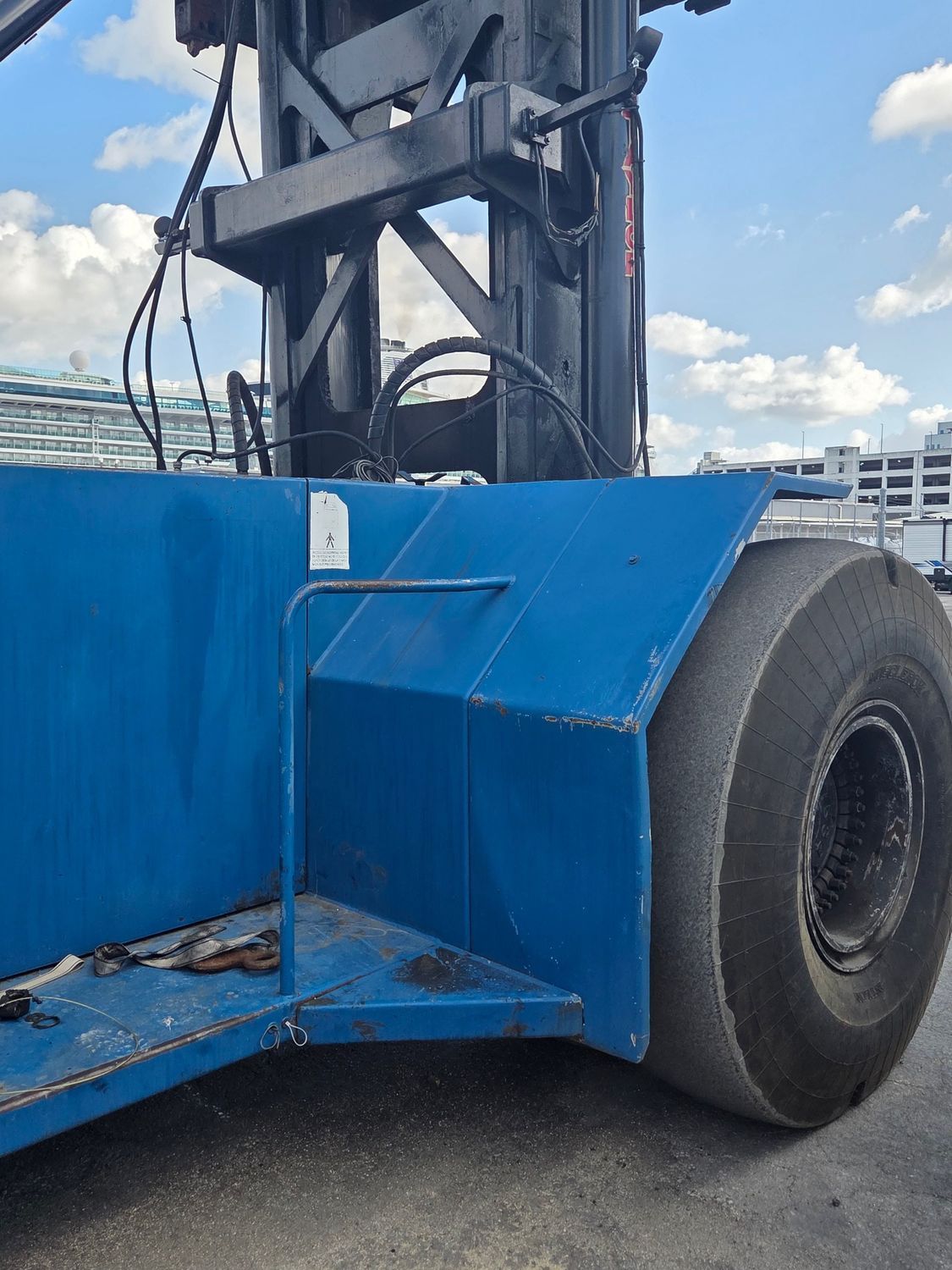 Blue industrial forklift, close-up view of a large tire and chassis.