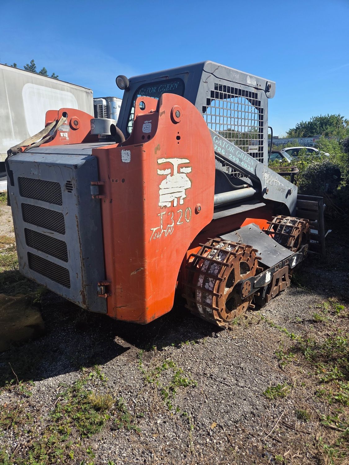 Orange and gray tracked skid steer loader on gravel.