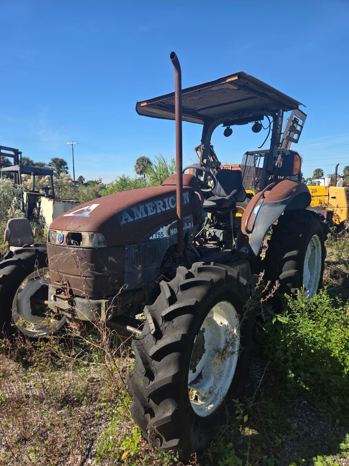 Rusty American tractor outdoors with white wheels and a canopy.