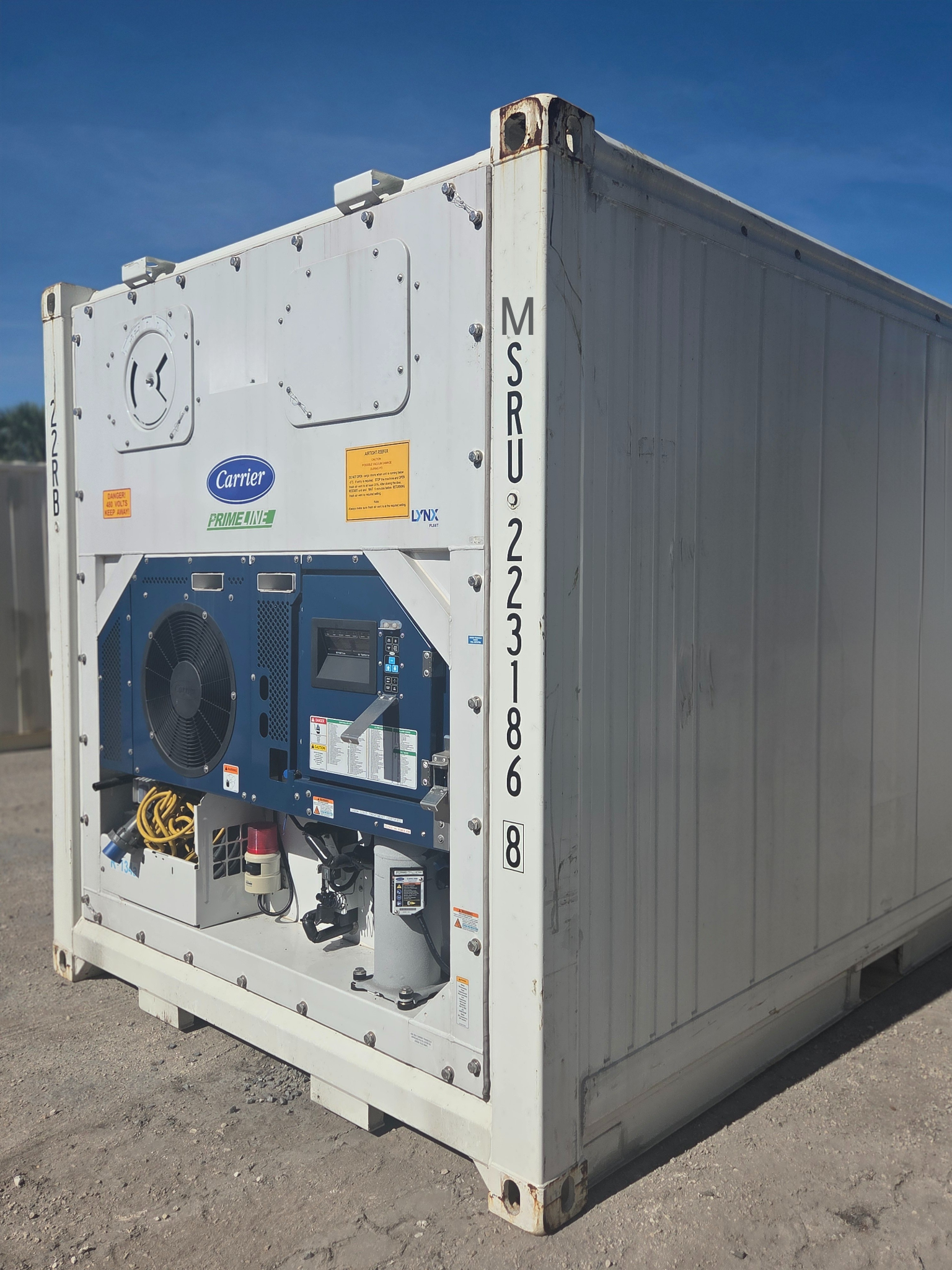 White refrigerated shipping container outdoors with cooling unit.