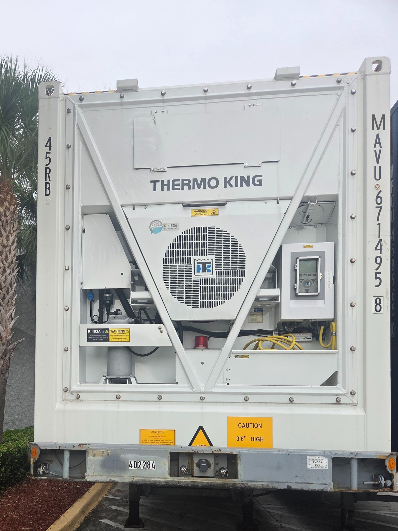White refrigerated shipping container with Thermo King unit and yellow warning labels.
