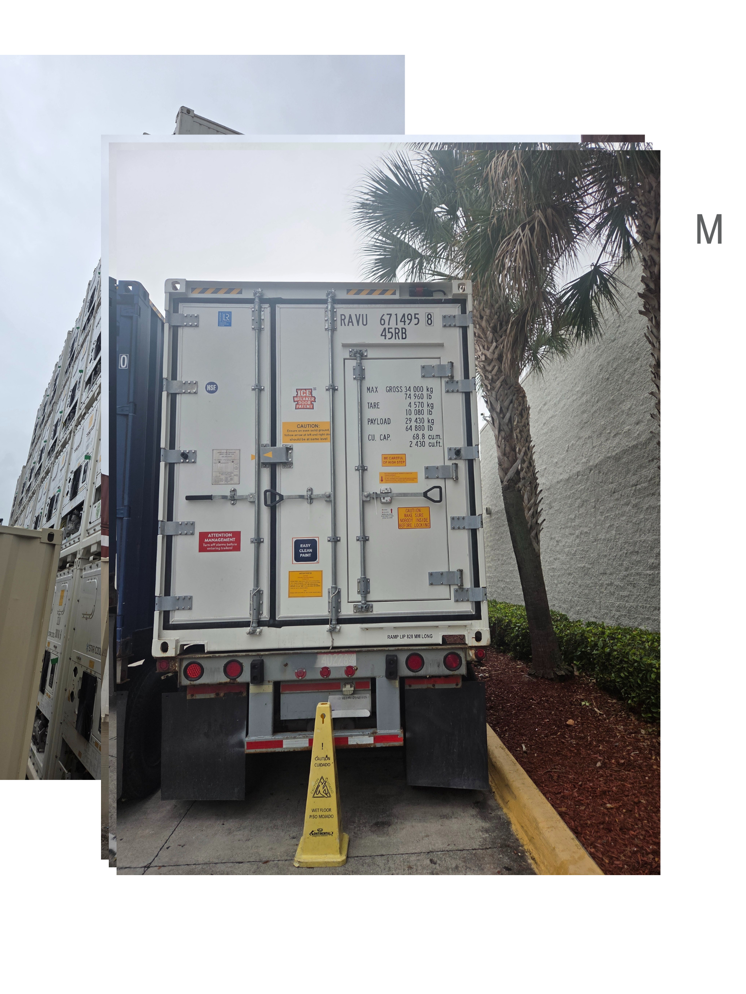 Rear view of a white refrigerated shipping container on a truck, open doors. A yellow cone is on the ground.
