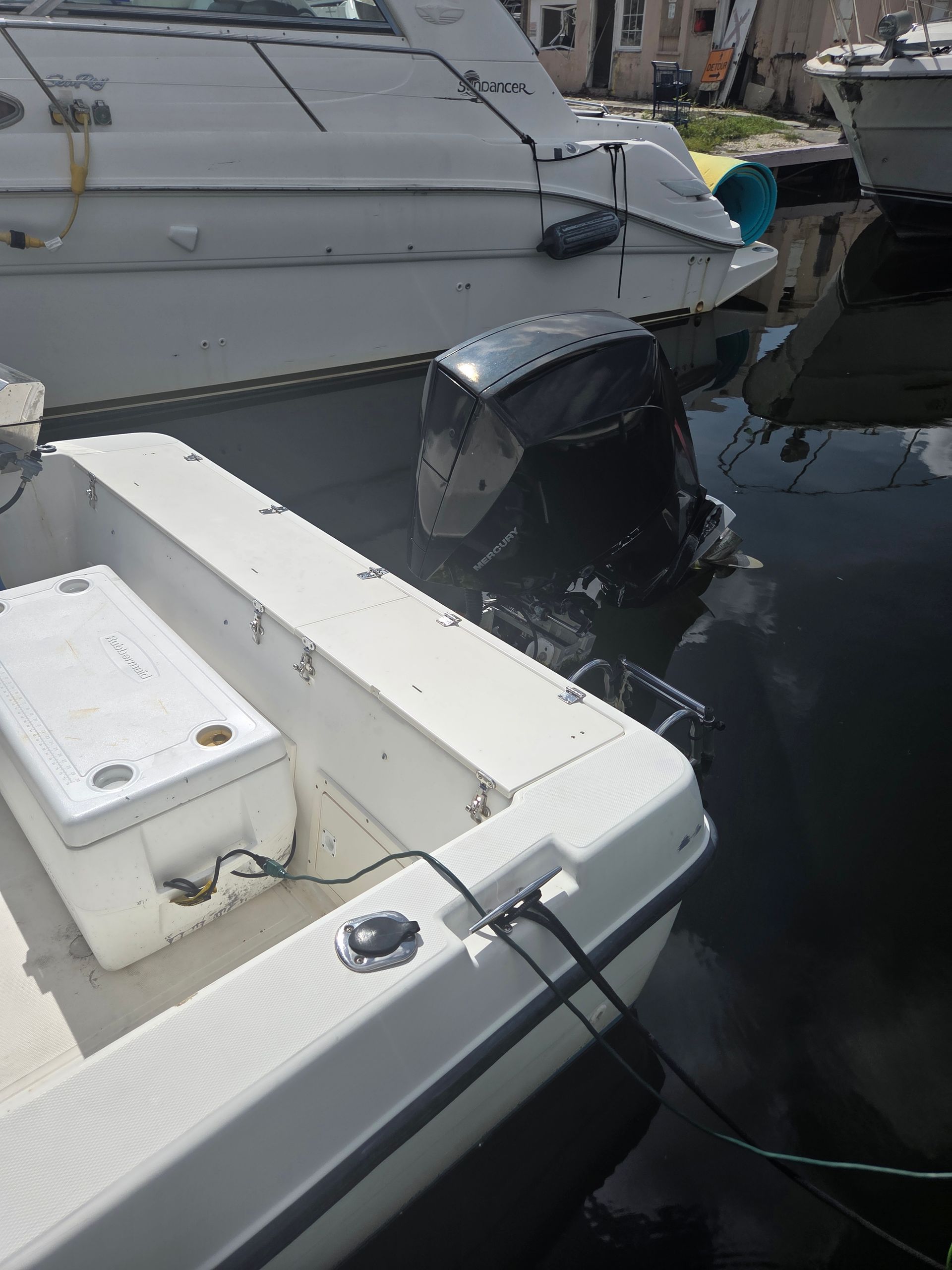 White motorboat tied up, with a larger boat behind it in a marina.