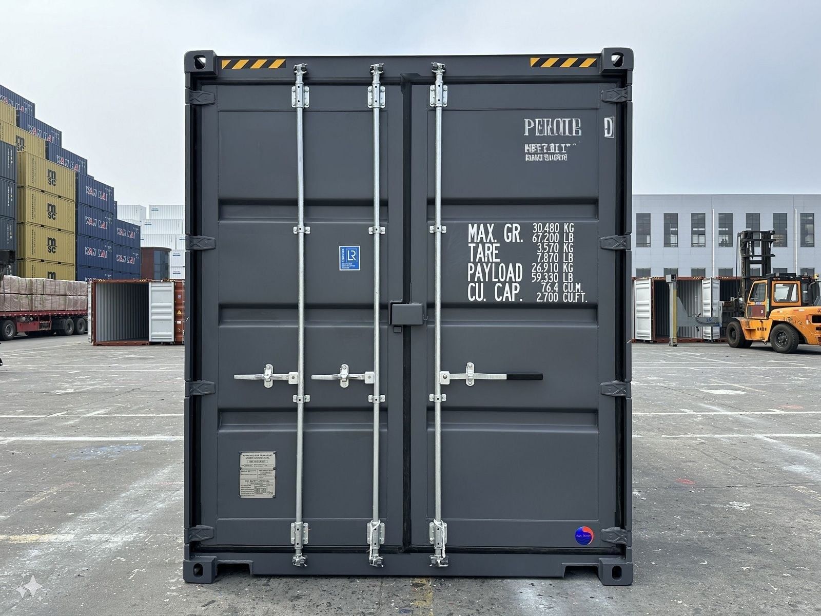 Dark gray shipping container with closed doors, in an outdoor industrial setting.