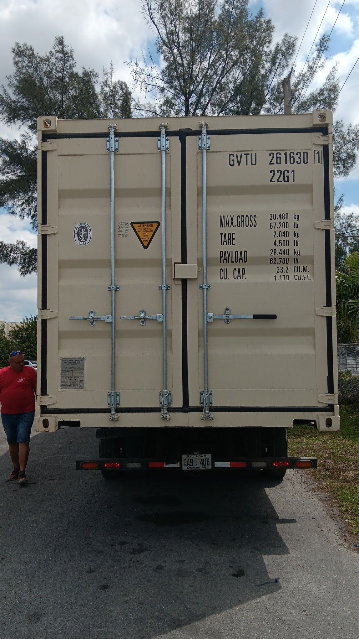 Tan shipping container on a truck, person standing beside it.