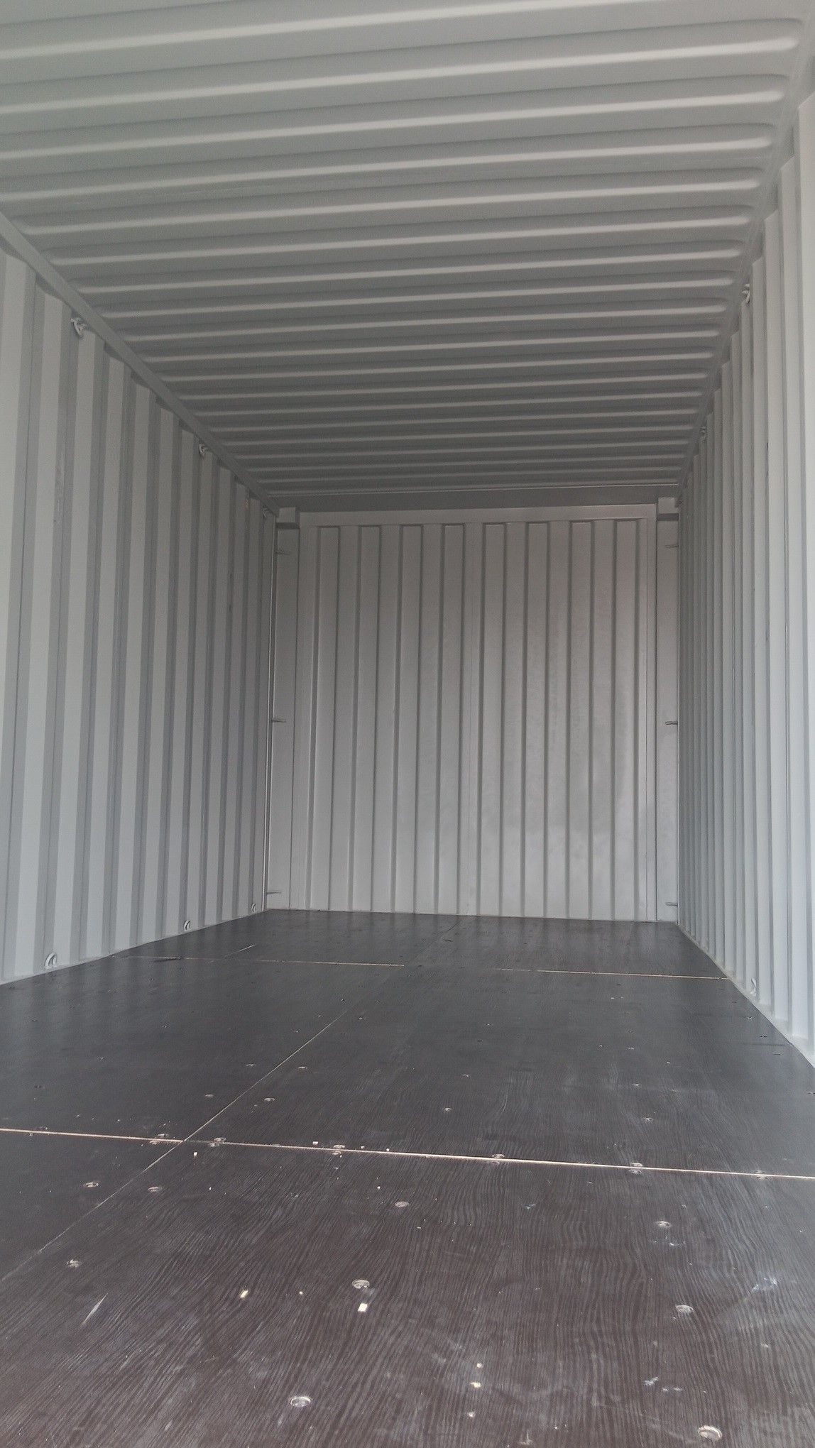 Empty shipping container interior with corrugated metal walls and dark floor.