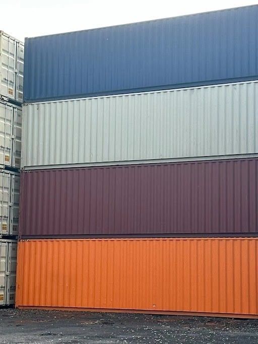 Stacked shipping containers in blue, cream, burgundy, and orange.