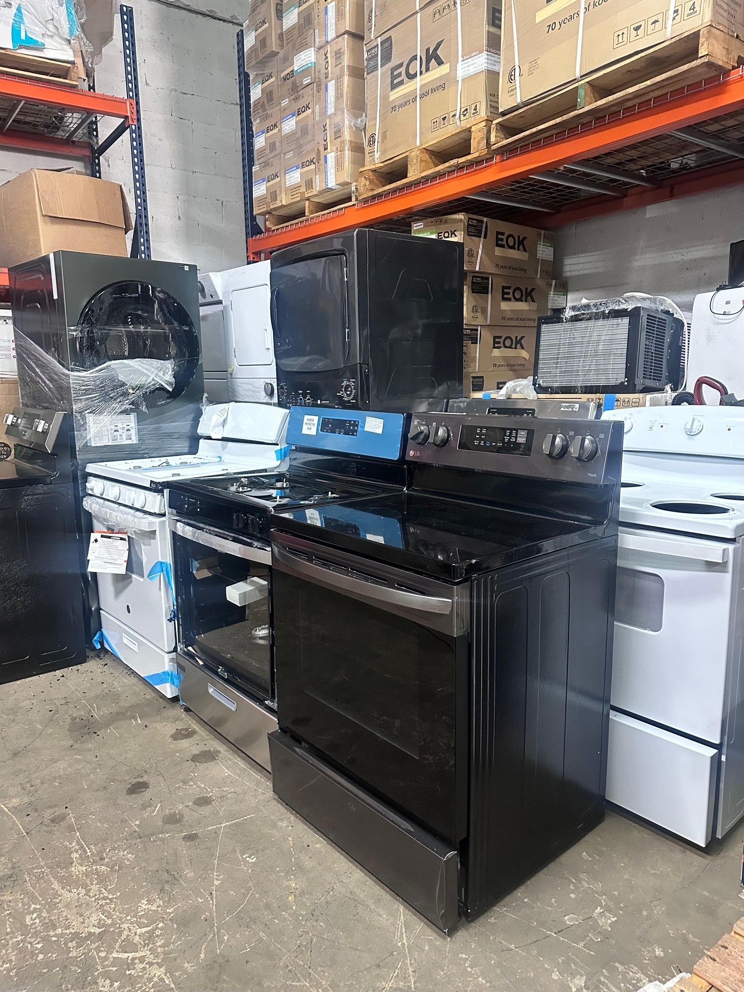 Various kitchen appliances, including ovens and stovetops, stacked in a warehouse setting.