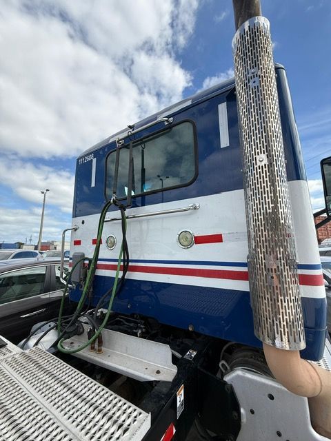 Blue and white semi-truck cab with chrome exhaust pipe.