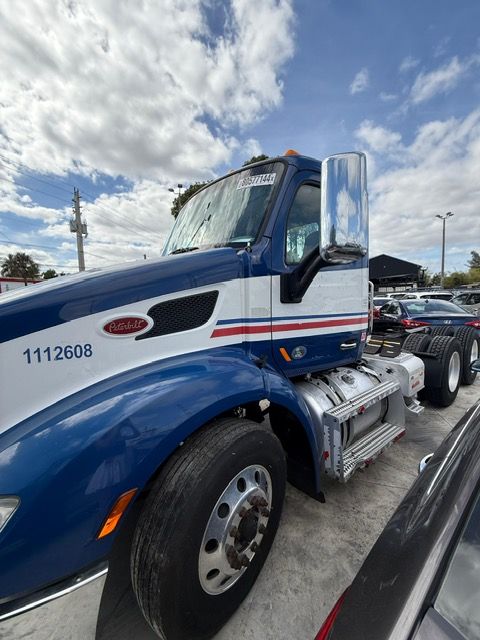 Blue and white Peterbilt semi-truck, parked outdoors under a cloudy sky.