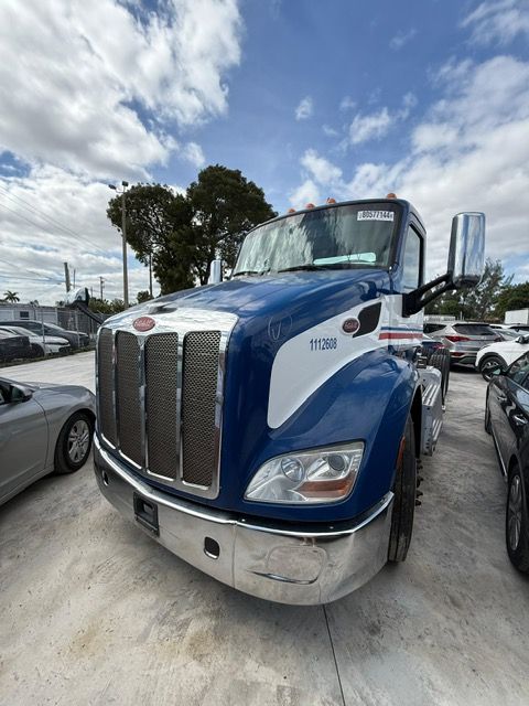 Blue and white Peterbilt 579 semi-truck, parked outdoors under a cloudy sky.