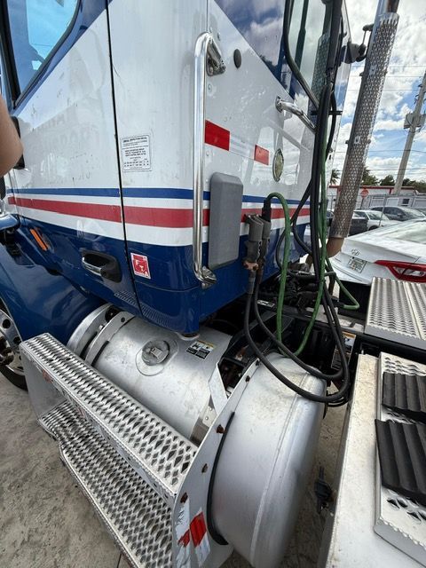 Blue and white semi-truck with a fuel tank and steps.