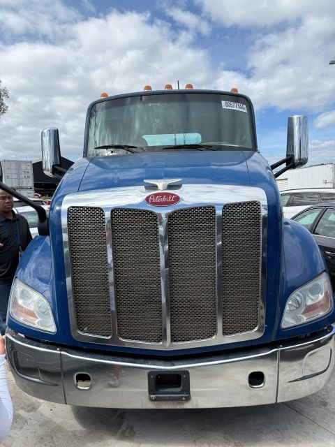 Blue Peterbilt truck, front view, chrome grill, overcast sky.
