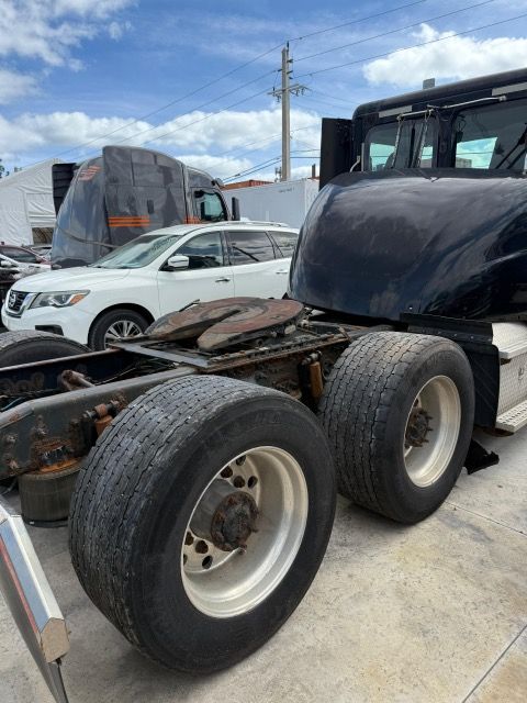 Rear view of a semi-truck cab with large tires and a fifth-wheel coupling, outdoors on a sunny day.