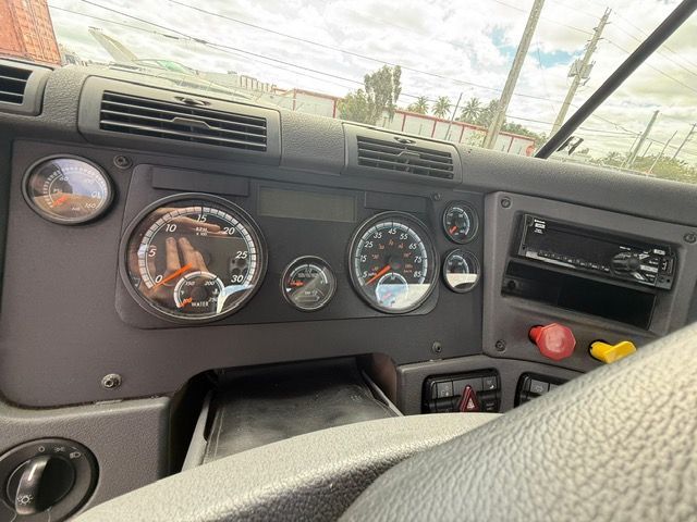 Dashboard of a truck, showing gauges, radio, and vents. Grey and black interior, windshield in the background.