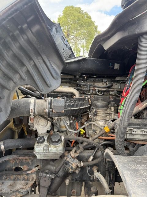 Open hood of a semi-truck revealing the engine and various components.