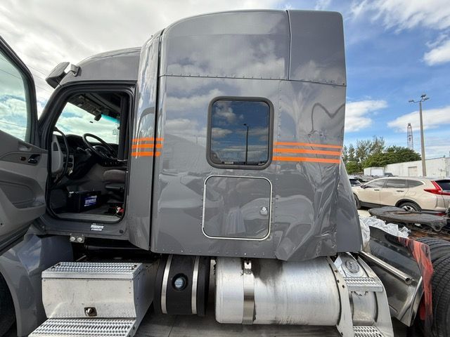 Gray semi-truck cab with orange stripes and open driver-side door.