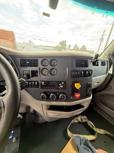Interior of a truck cab, dashboard with gauges, radio, and air brake controls.