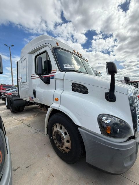White semi-truck cab parked outside on a cloudy day.