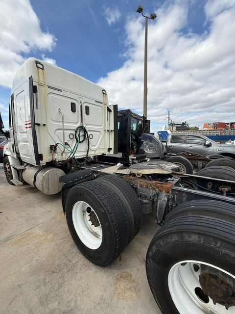 White semi-truck cab with dual rear tires, parked outside on a cloudy day.
