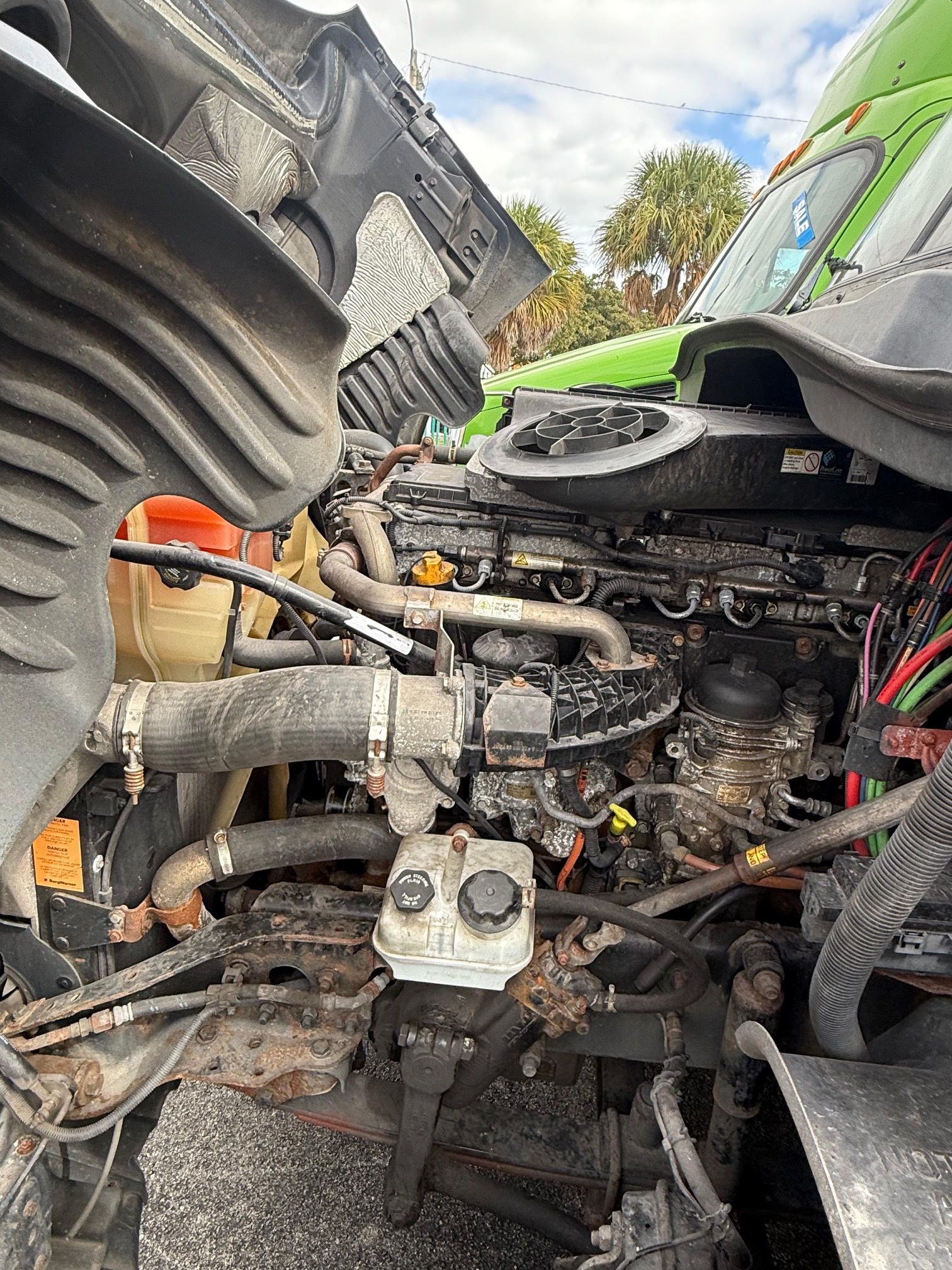 Open truck engine, black and silver components, with green cab visible.