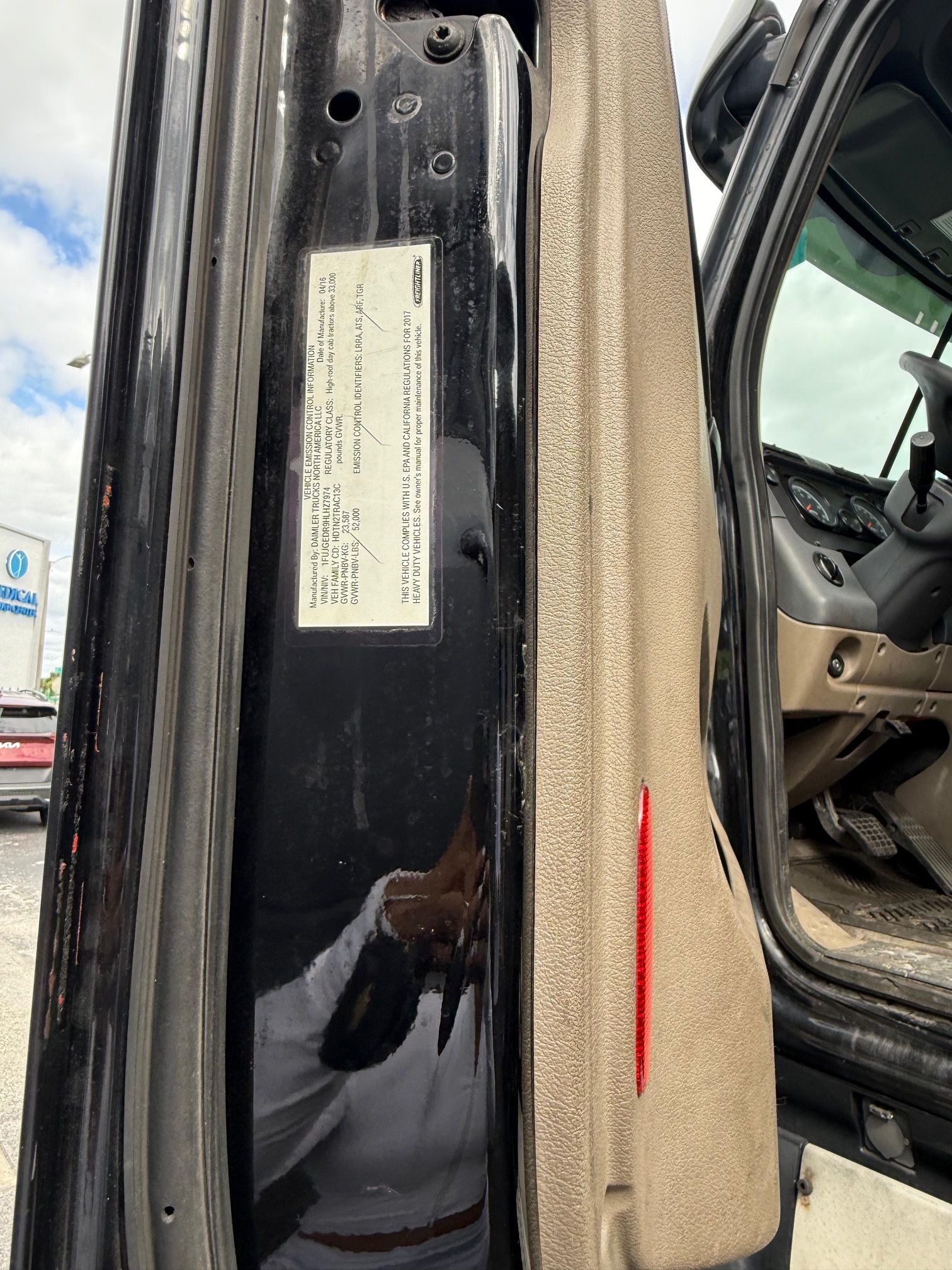 Black truck door frame with sticker, red line, and interior details visible.