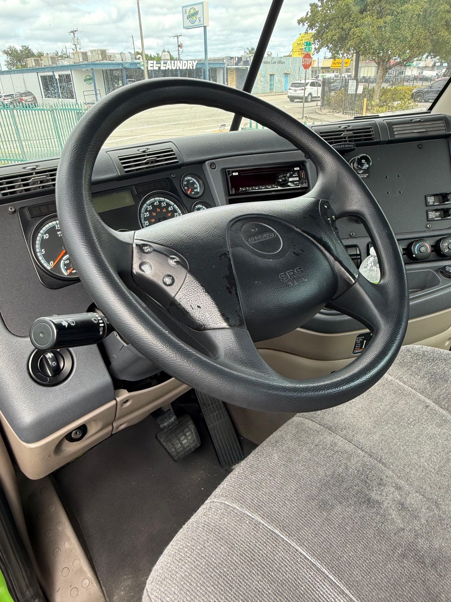 Interior of a truck cab, focus on the steering wheel, dashboard, and seat.