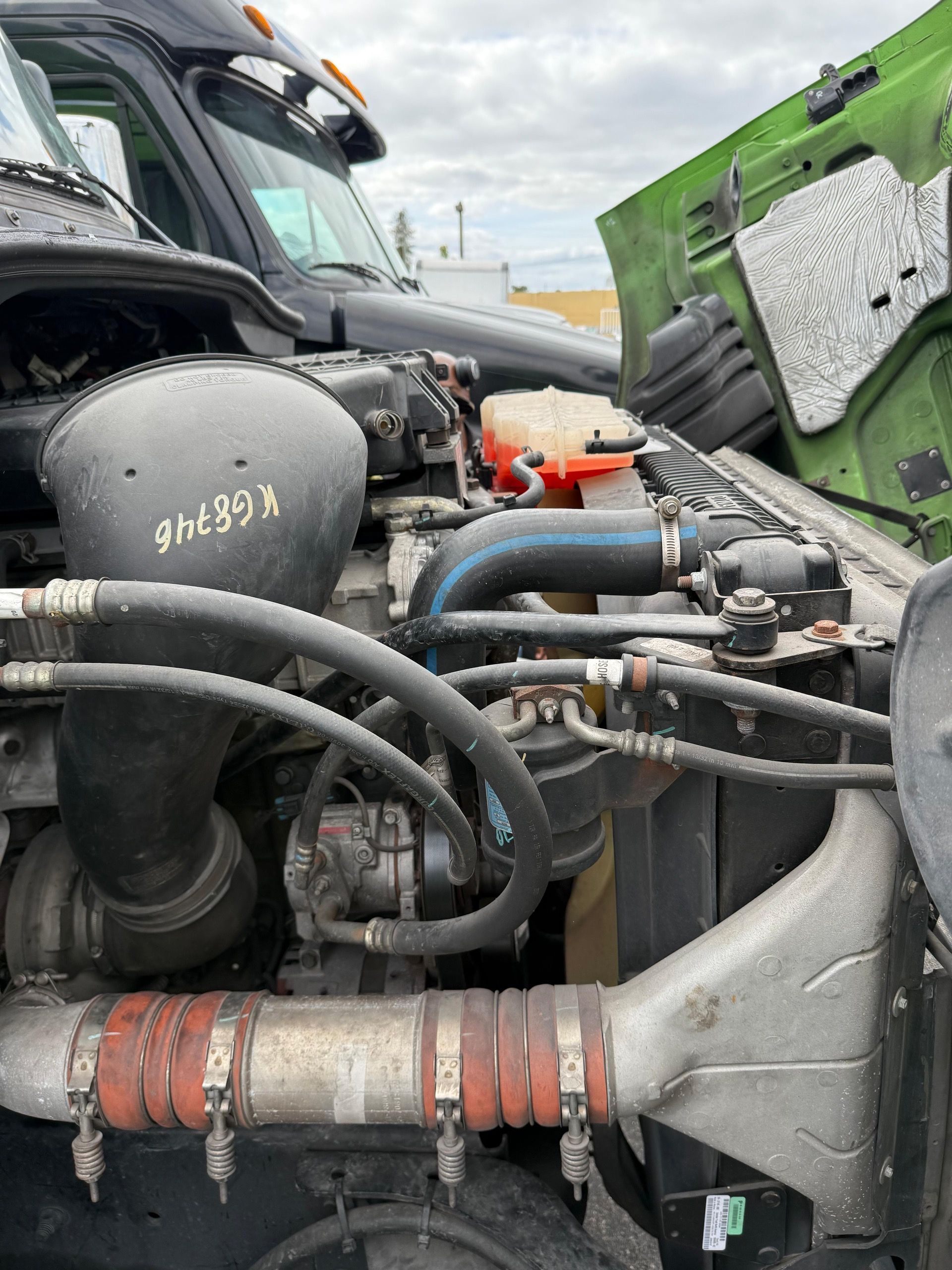 Engine bay of a semi-truck with the hood open, featuring various components and hoses.