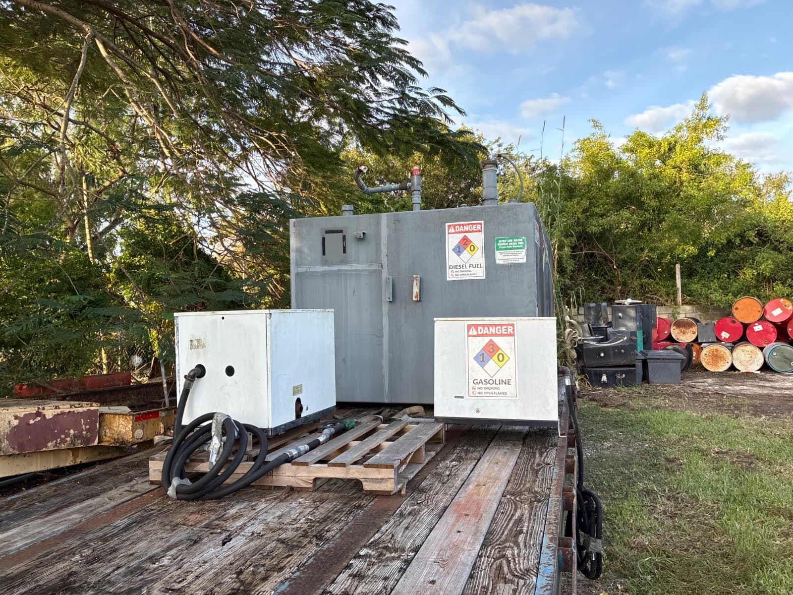Tank and containers on a trailer; includes hazard labels, and is outdoors.