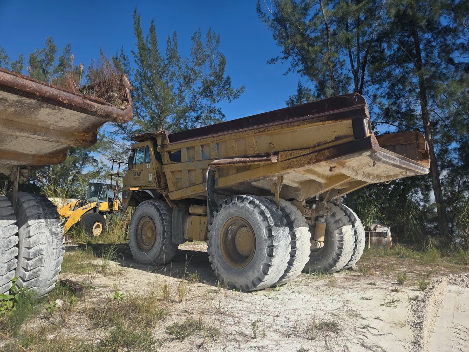 Yellow dump truck parked on a construction site, with large tires.