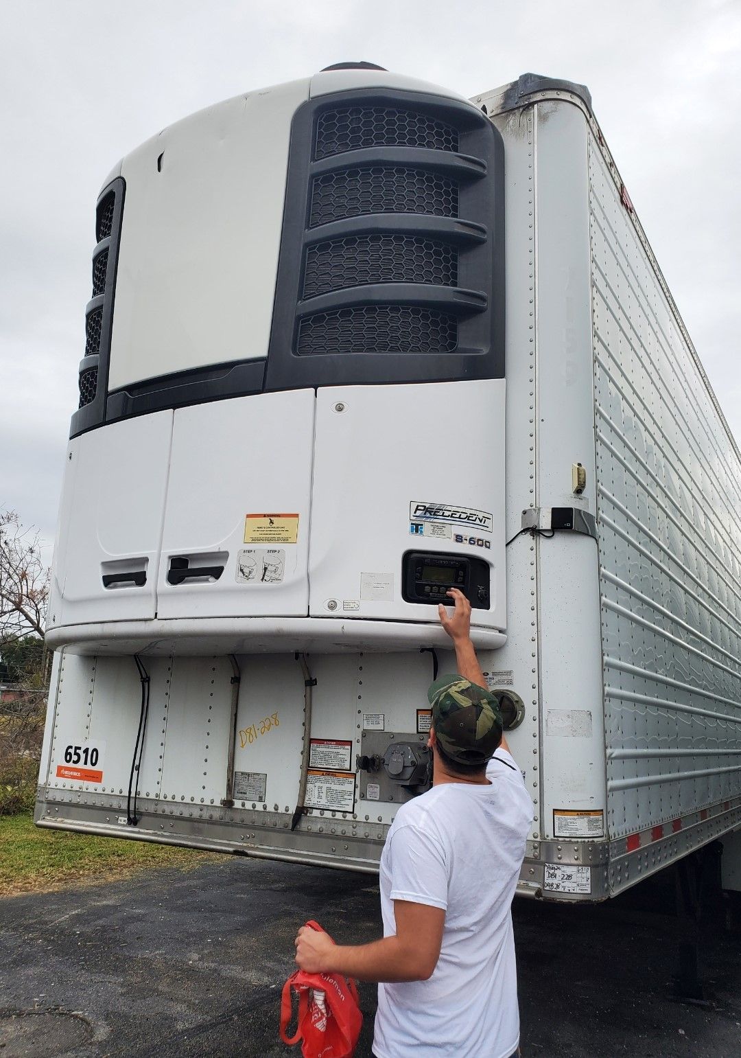 Person with red can near a refrigerated truck unit.