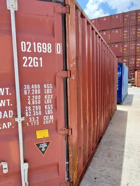 Red shipping container with markings, standing outside.