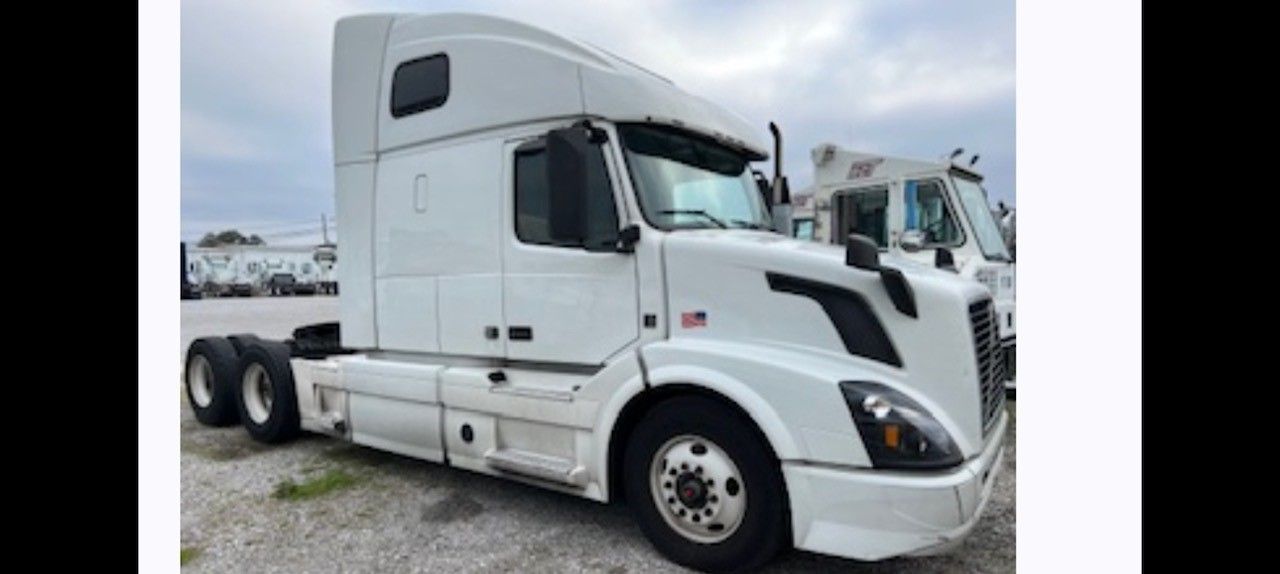 White semi-truck parked in a lot under a cloudy sky.