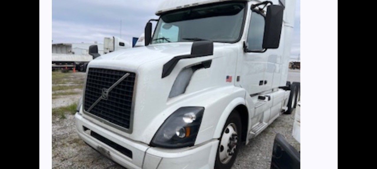 White Volvo semi-truck parked outdoors on a cloudy day.
