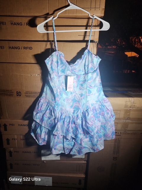 Light blue floral mini dress on a hanger, in front of stacked cardboard boxes.