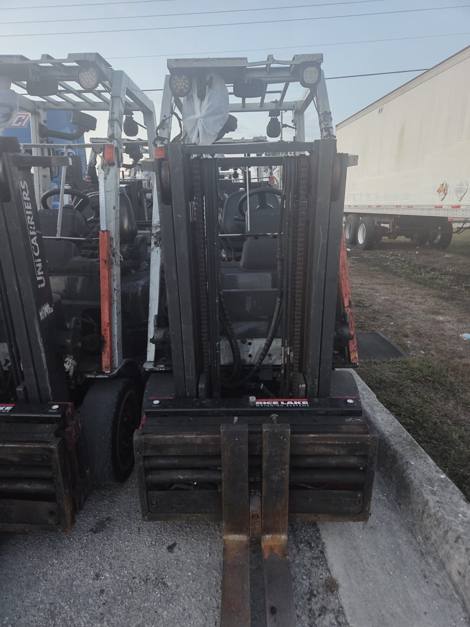 Forklift parked outside, another partially visible behind it. Gray concrete.