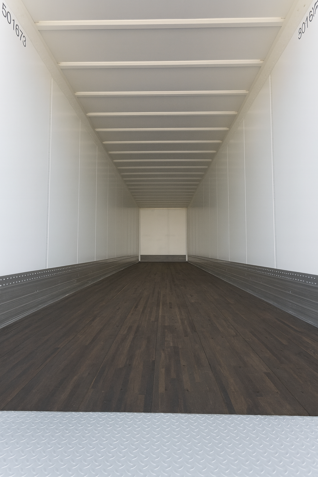 Empty white semi-trailer interior with dark wood-grain flooring and metal side panels.