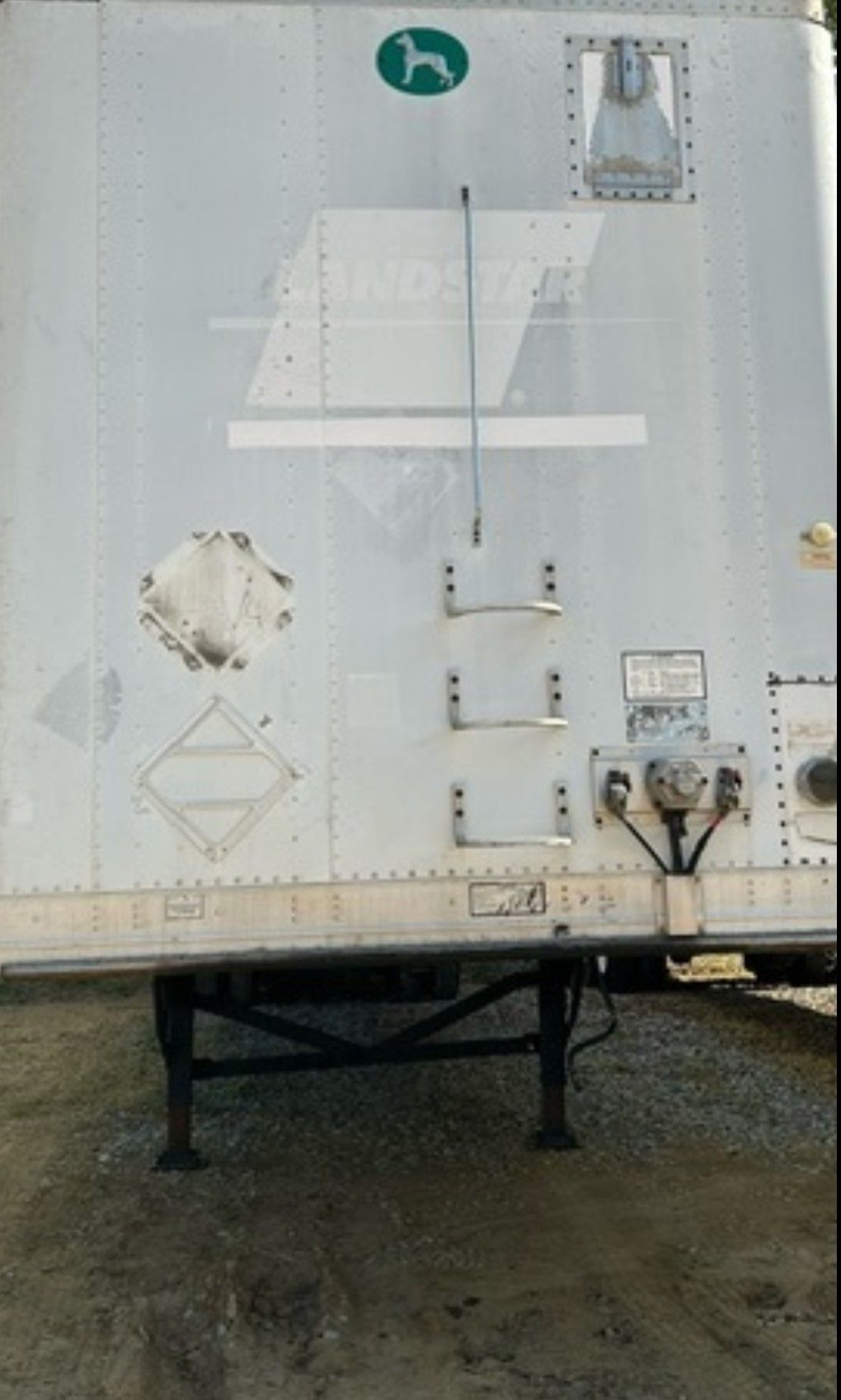 White semi-trailer with ladder and green dog logo on side.