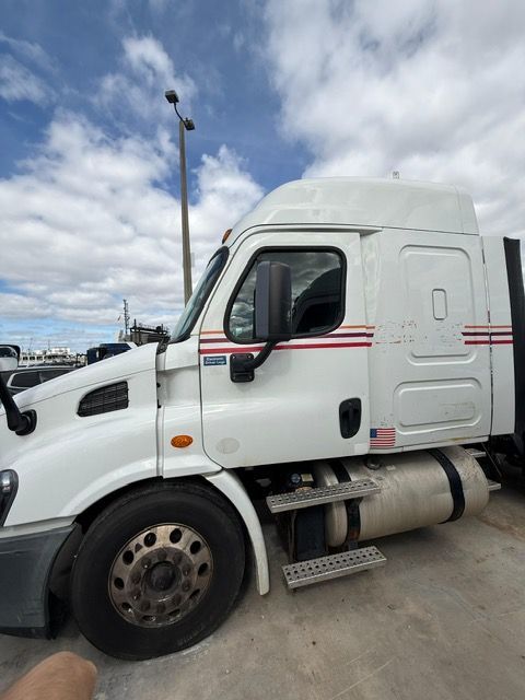 White semi-truck parked outdoors on a cloudy day, with red stripes on the side.