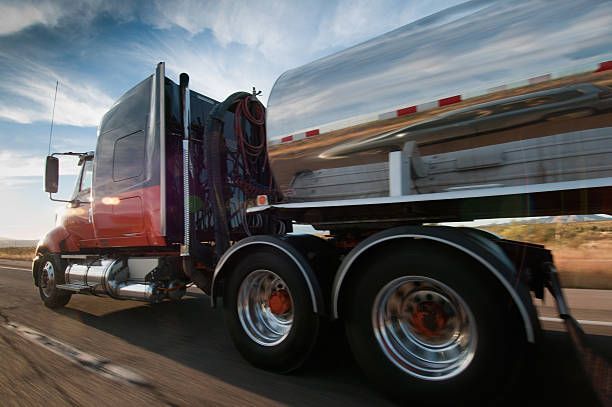 A semi truck is driving down a road with a large tank on the back.