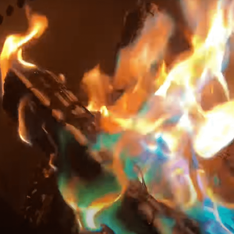 Bright flames with blue and green hues burning from a log.