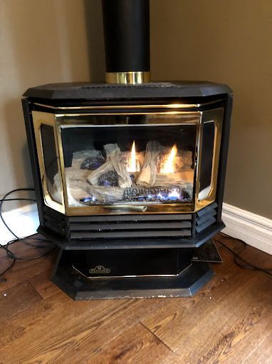 A gas fireplace is sitting on a wooden floor in a room.