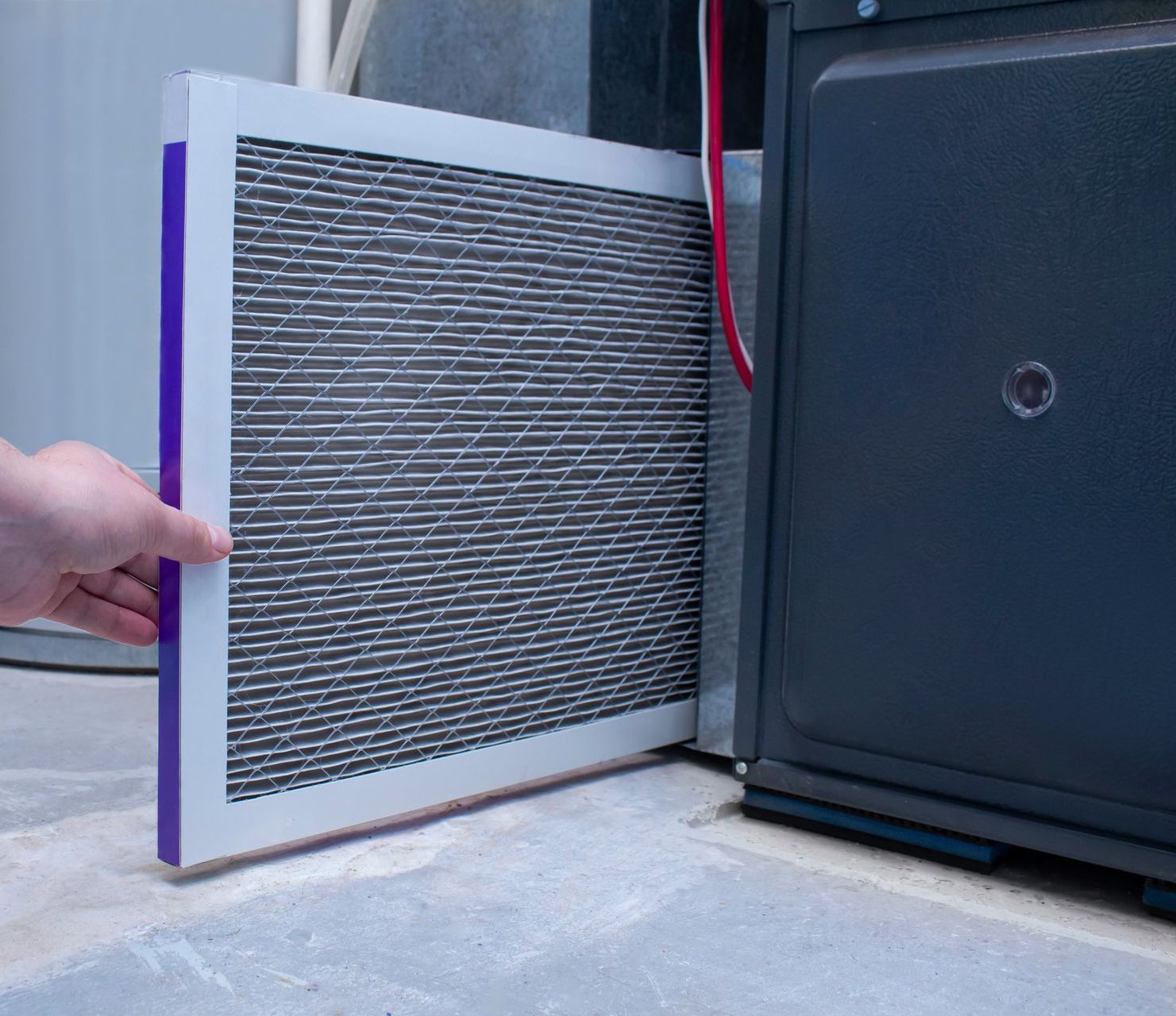 A person is holding a filter in front of a furnace.
