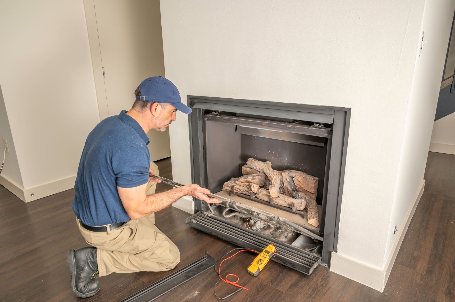A man is kneeling down in front of a fireplace in a living room.